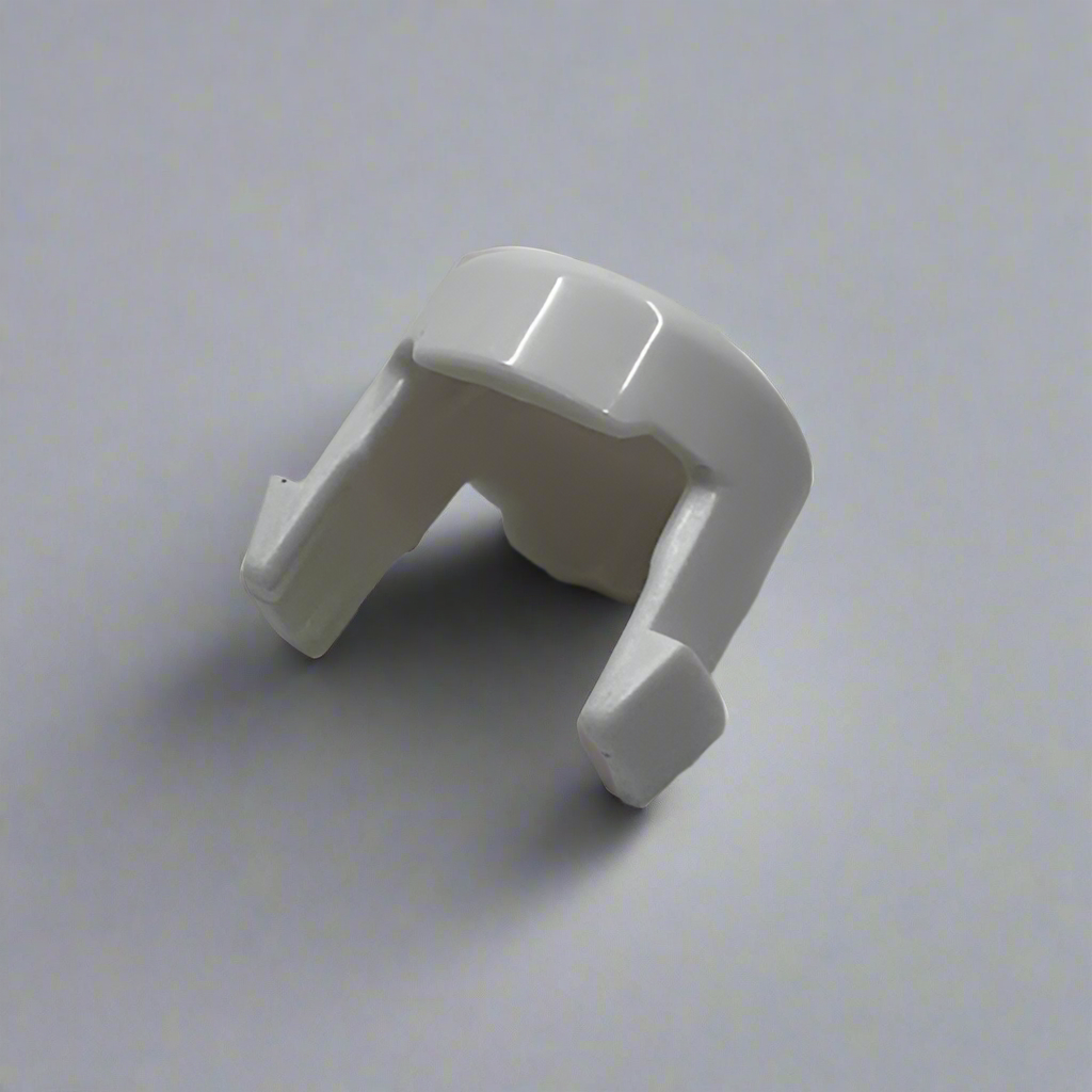 White plastic babyzen pushchair button  on a grey surface
