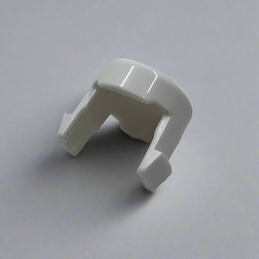 White plastic babyzen pushchair button  on a grey surface